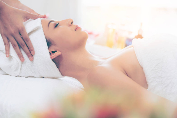 Relaxed young woman lying on spa bed prepared for facial treatment and massage in luxury spa resort. Wellness, stress relief and rejuvenation concept. - Foto, immagini