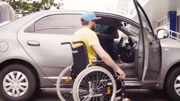 Ένας άντρας σε μια αναπηρική καρέκλα και μια γυναίκα κοντά στο αυτοκίνητο - Πλάνα, βίντεο