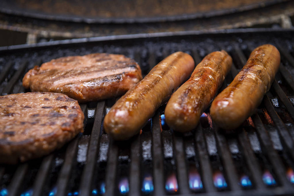 Domuz sosisi ve taşınabilir bir barbekü üzerinde ızgara burger kadar yakın ızgara, et ve yangın - Fotoğraf, Görsel