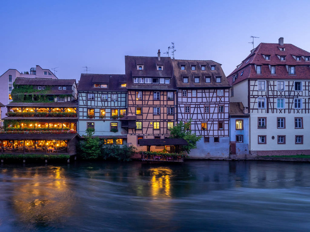 Sonnenuntergang entlang des kranken Flusses in petite france Gegenden von Straßburg im Elsass. die Häuser sind die traditionellen Fachwerkhäuser, die überall in diesem Gebiet von Frankreich sichtbar sind. - Foto, Bild