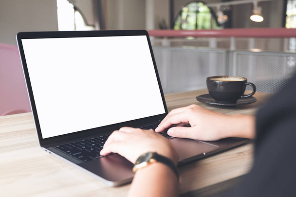 Imagen burlona de una mujer de negocios usando y escribiendo en el ordenador portátil con pantalla de escritorio blanco en blanco con taza de café en la mesa de madera en la oficina - Foto, imagen