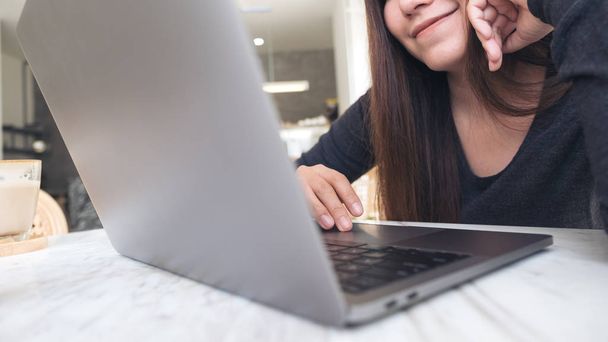 Imagen de cerca de una mujer que usa y mira el ordenador portátil con sentirse feliz en la cafetería - Foto, imagen