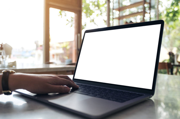 Mockup-Bild der Hände mit und Tippen auf Laptop mit leerem weißen Desktop-Bildschirm auf dem Tisch in einem modernen Café - Foto, Bild