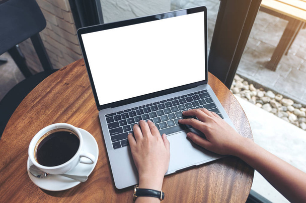 Top view makieta obrazu kobiety korzystającej i piszącej na laptopie z białym ekranem pulpitu na drewnianym stole w kawiarni - Zdjęcie, obraz