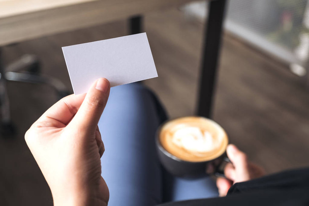 Mulher segurando um cartão de visita vazio enquanto bebe xícara de café - Foto, Imagem