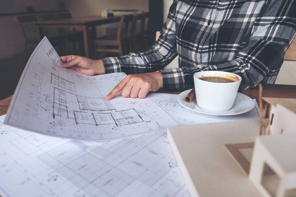 Egy építész dolgozik egy architektúra modell bolt rajz papír és kávéscsésze az asztalon - Fotó, kép
