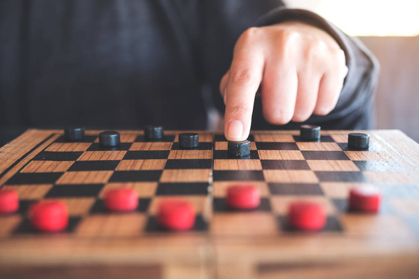 Closeup image of people playing and moving checkers in a chessboard - Photo, Image