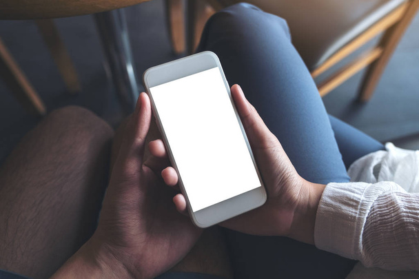 Mockup image of man and woman's hands holding and looking at white mobile phone with blank desktop screen together  - Photo, Image