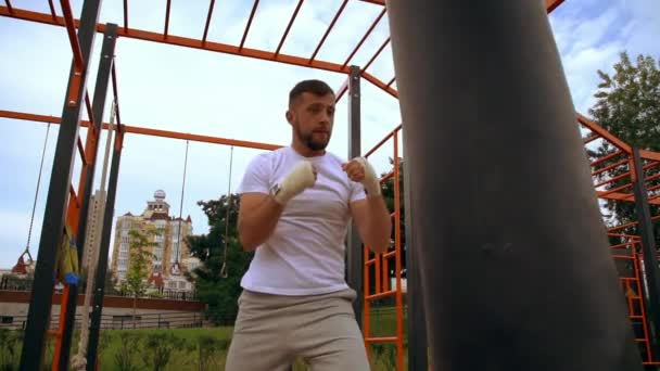 man using his strength to punch a punchbag - Video