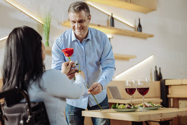 Cheerful man presenting a flower to a woman - Foto, Imagem