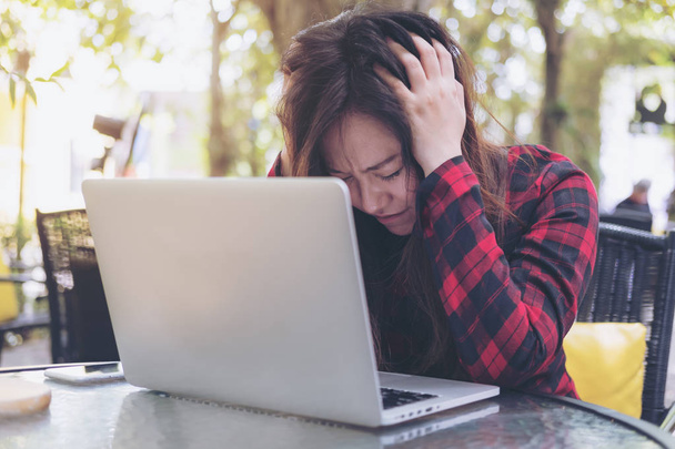 Ve yorgun, stresli duygu ile bir Asya iş kadını closeup görüntüsünü kapatın gözleri yeşil doğa arka plan ile açık oturan cam masa laptop kullanırken - Fotoğraf, Görsel