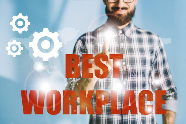 cropped view of businessman in checkered shirt pointing at "best workplace" with gears - Foto, Imagen