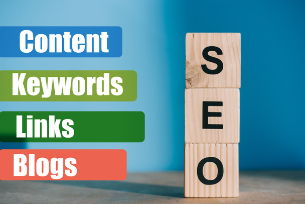 SEO word made from wooden blocks on blue background with Content, Keywords, Links, Blogs signs - Photo, Image