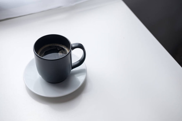 Крупним планом зображення чорної гарячої чашки кави з білою тарілкою на старовинному дерев'яному столі та фоні штор у мінімалізмі кафе
 - Фото, зображення