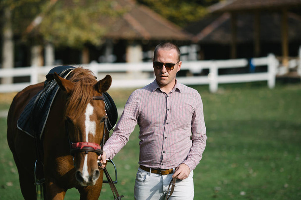 Elegant casually dressed man with brown horse - Foto, afbeelding