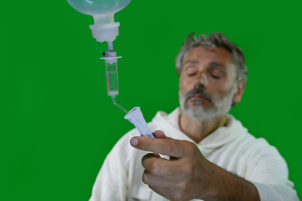 Male nurse or doctor is checking the drip-feed  over green background - Zdjęcie, obraz