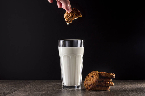 Oatmeal cookies and glass of milk on a wooden table on a black background. - Foto, Imagem