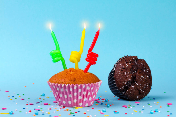 Muffins and burning candles on their birthday on a blue background. - Foto, Bild