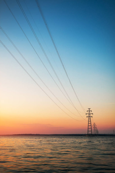 Lignes électriques de la centrale nucléaire à l'autre rive. Beau paysage avec coucher de soleil et un lac
. - Photo, image