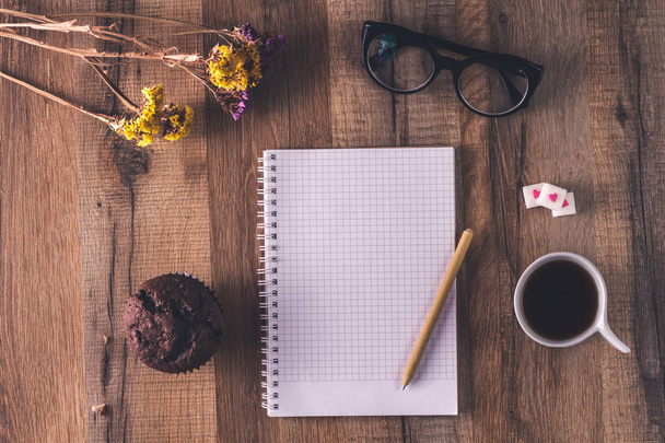 Beautiful hipster flat lay with coffee, chocolate maffin, notebook, spectacles and flowers. Working space surface top view. Creative work table for blogger.  - Φωτογραφία, εικόνα