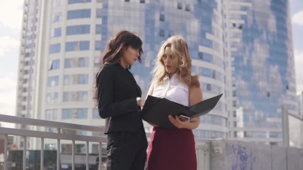 informal meeting of business partners on the background of the business center. two business women in formal suits talking outdoor - Footage, Video