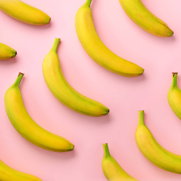 Colorful fruit pattern. Bananas over pink background. Square crop. Top view. Pop art design, creative summer concept. Minimal flat lay style - Valokuva, kuva