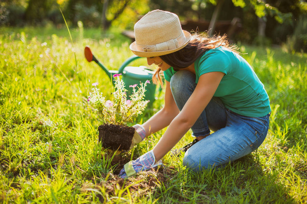 Young happy woman is planting a flower in her garden.  - Φωτογραφία, εικόνα