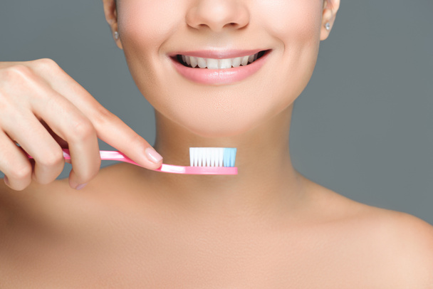 recortado disparo de sonriente mujer sosteniendo cepillo de dientes en la mano aislado en blanco
 - Foto, Imagen
