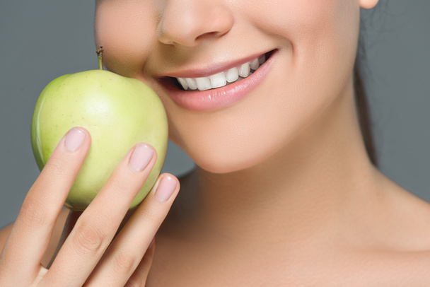 visão parcial de mulher com dentes brancos e maçã fresca isolada em cinza
 - Foto, Imagem