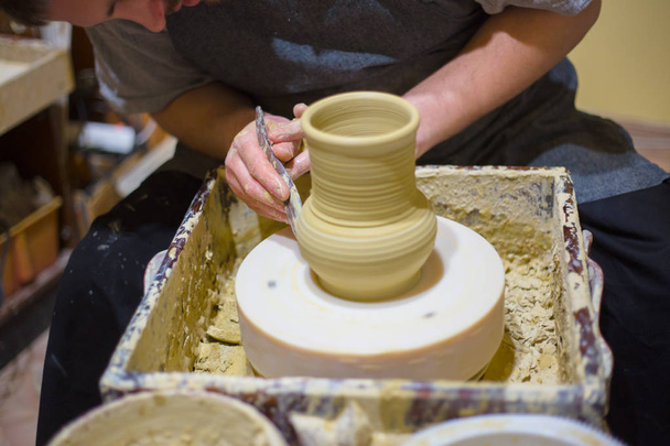 Professional potter shaping jug with special tool in pottery workshop - Фото, зображення