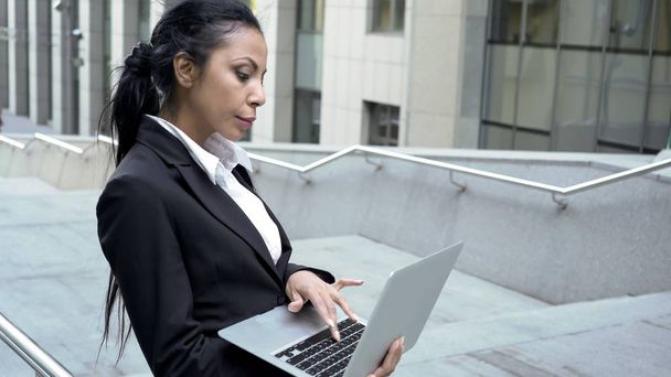 Successful business lady working on laptop outside business center, technology - Foto, imagen