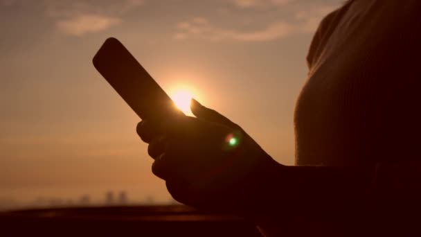 meçhul kişi Smartphone günbatımı arka plan kullanarak - Video, Çekim