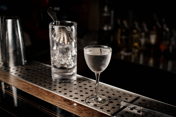 Елегантний коктейльний келих, наповнений свіжим і міцним алкогольним напоєм на розмитому фоні бару
 - Фото, зображення