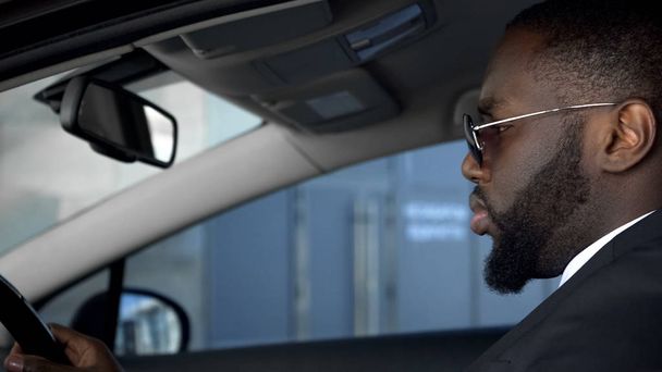 Serious African American man driving automobile, looking attentively at road - Foto, Bild