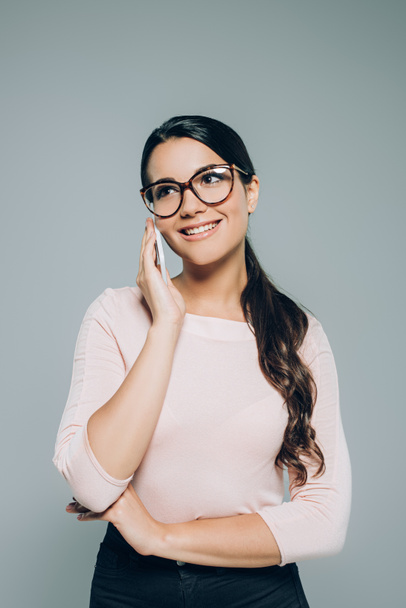 beautiful smiling woman in eyeglasses talking on smartphone, isolated on grey - Foto, Bild