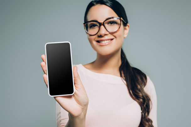 Młoda kobieta pokazując smartphone rezygnować pusty ekran, na szarym tle - Zdjęcie, obraz