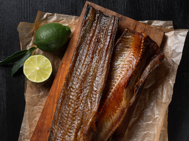 Smoked sea fish with green lime on dark background - Foto, imagen