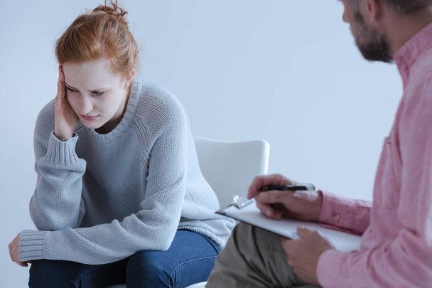Young woman with emotional problems thinking about the future and talking to a psychologist during an individual therapy meeting. - Photo, image