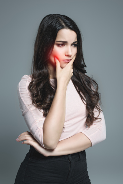jonge vrouw lijdt aan kiespijn met rode pijnlijke punt, geïsoleerd op grijs - Foto, afbeelding