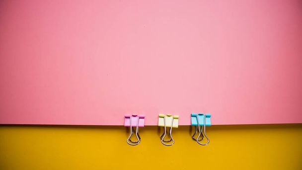 Fondo amarillo rosado multicolor con tres abrazaderas de oficina
 - Foto, Imagen