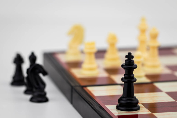 Pieza de ajedrez King con figuras de ajedrez de pie sobre una mesa blanca en una imagen conceptual
. - Foto, imagen