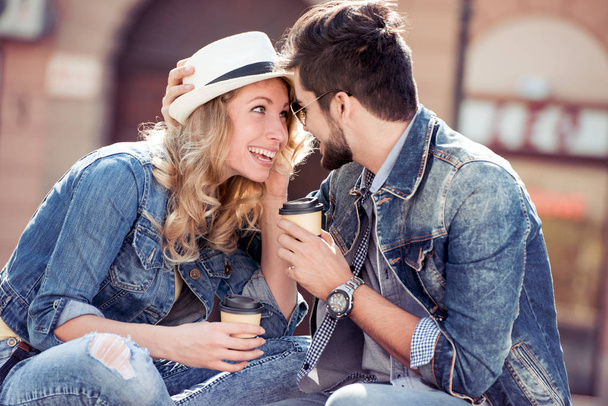 コーヒーを飲むと、市の公園で座っている若いカップル. - 写真・画像