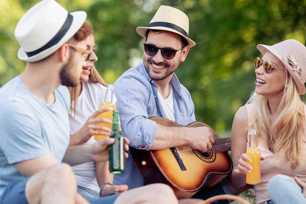 Vrolijke groep vrienden met gitaar plezier op picknick - Foto, afbeelding