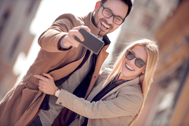 Happy couple of tourists taking selfie in the city. - Fotó, kép