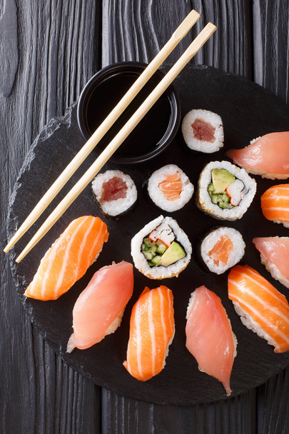 Sloužil řadu sushi s lososem a tuňáků, Kalifornie válců, maki, sójová omáčka detailní na černé břidlicové desky na stole. Vertikální pohled shora z Vihorlatské vrchy - Fotografie, Obrázek