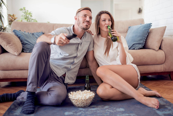 Attractive young couple sitting on the floor,watching tv. - Foto, Imagen