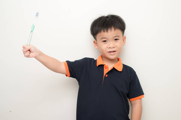 Vrolijk jongetje houden van een tandenborstel over witte achtergrond, Studio portret van een jongen met gezonde gemengd ras met een tandenborstel geïsoleerd. - Foto, afbeelding