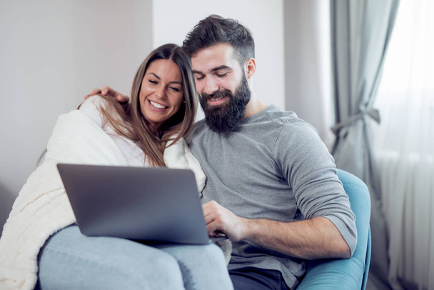 Casal assistindo a um filme no laptop em sua sala de vida.Amor, tecnologia, internet e conceito de pessoas
. - Foto, Imagem