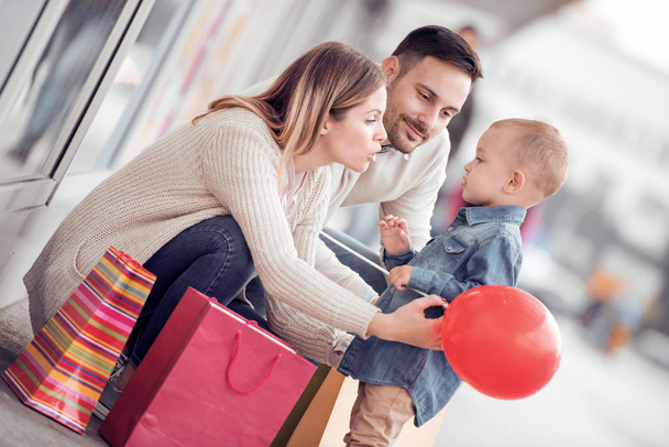 Venda, consumismo e conceito de família - família feliz com criança pequena e sacos de compras na cidade
. - Foto, Imagem