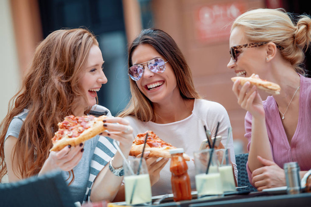 Onnellinen nainen ystävät syövät pizzaa kahvilassa
. - Valokuva, kuva